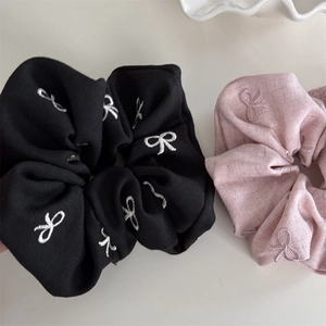 Gros plan de chouchous en tissu avec d'élégants détails de broderie de papillon blanc