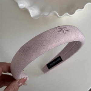Détail du serre-tête rembourré rose avec nœud brodé et étiquette fait main