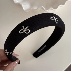 Détail du bandeau noir fait main avec broderie blanche et étiquette textile handmade
