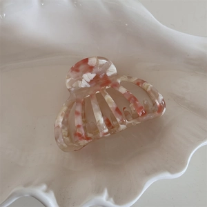 Detail of orange shell patterned acetate hair claw clip on a white decorative tray