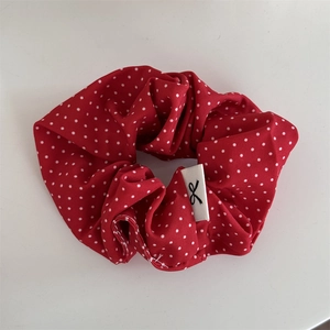 Vue détaillée d'un chouchou rouge à pois avec étiquette blanche sur fond blanc pur