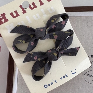 Detalle de dos pinzas para el pelo de pana gris oscuro con flores en tarjeta