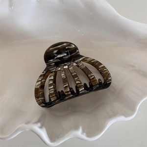 Detail view of acetate shell hair claw with marble texture on a ceramic tray