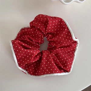 Gros plan sur un chouchou rouge à pois avec liseré blanc et texture textile souple