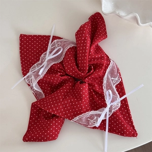 Détails d'un chouchou rouge à pois avec bordure en dentelle blanche et petits nœuds