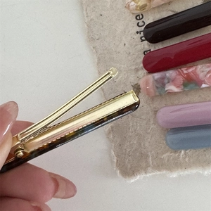 Detailed close-up of the golden alloy spring teeth mechanism on acetate hair clips