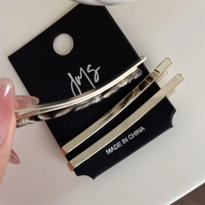 Close-up of three elegant hair clips with marble texture and gold finish on card