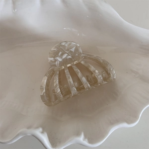 Detail of shell-shaped acetate hair claw clip with marble texture in a ceramic dish