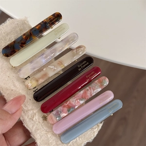 Close-up of rectangle acetate hair clips in multiple colors with golden French lettering