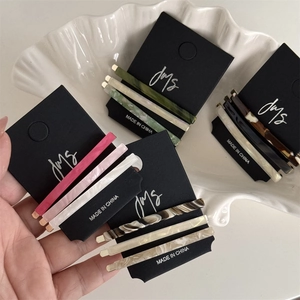 Detailed view of three minimalist acetate hair clips with marble patterns on black card