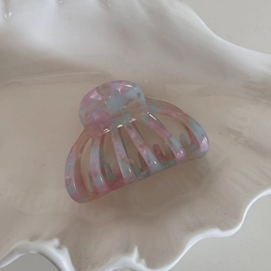 Close-up of hollow shell hair claw clip with colorful marble acetate texture on shell tray