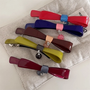 Détail de barrettes nœuds avec pendentifs en perles sur un petit sac en tissu gris
