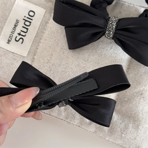 Détail du nœud papillon en satin noir avec strass et pince crocodile en métal robuste