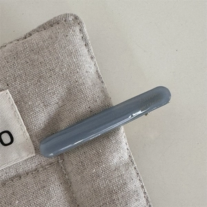 Macro detail of a minimalist grey acetate hair clip on a textured linen background