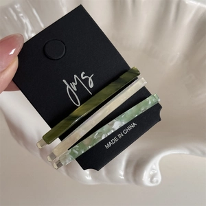 Detailed macro view of three minimalist acetate bobby pins on a premium display card