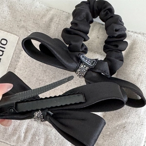 Détail de barrette et chouchou en satin noir faits main avec des diamants étincelants