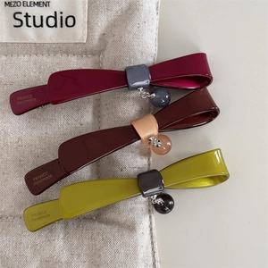 Détails de trois barrettes en résine polie aux couleurs bordeaux, marron et verte