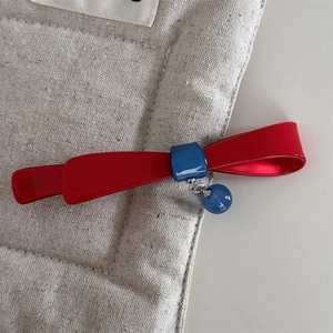 Détail de la barrette à nœud rouge avec breloque bleue et gravure France Handmade