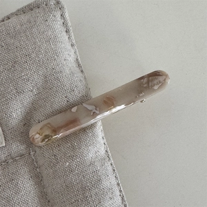 Detailed macro view of the marble texture and gold foil inlay on the resin hair clip
