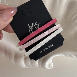 Detailed view of three minimalist acetate hair clips in pink and white marble finish