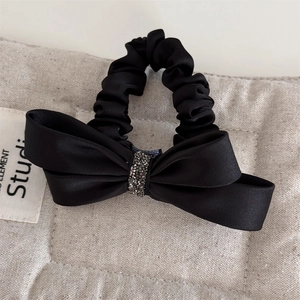 Gros plan d'une barrette à cheveux en satin noir avec détails en strass brillants