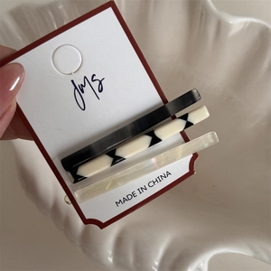 Detailed view of three minimalist acetate hair clips in pearl white and geometric patterns