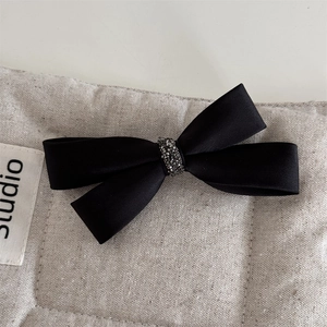 Détail d'un n’ud papillon en satin noir avec strass scintillants sur le centre de pince