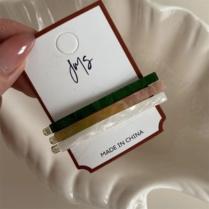 Detail of 3-piece acetate hair clips in marble green, pink and pearl white finish