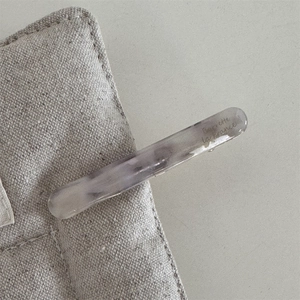 Macro detail of marble pattern acetate barrette with Barrette la France logo text