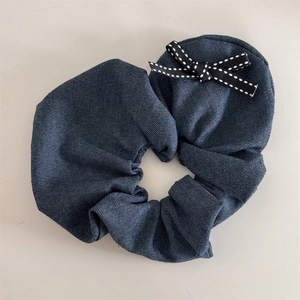 Primo piano di un elastico per capelli in denim blu con fiocco a pois bianchi e neri
