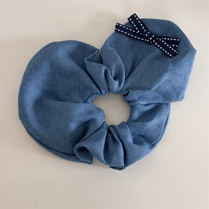 Dettaglio di scrunchie in denim blu con fiocco a pois bianchi come accessorio per capelli