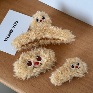 Plush brown bear hair clip set featuring three cute cartoon monster styles on wood