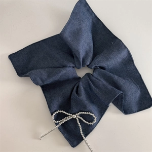 Dettaglio scrunchie in denim blu scuro con fiocco in catena di perline argentate decorativo
