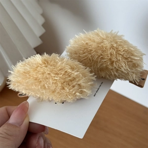 Detailed macro view of two soft honey-yellow plush bear hair clips on a gift card