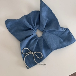 Dettaglio di elastico per capelli in denim blu con ricamo di perle argentate a fiocco