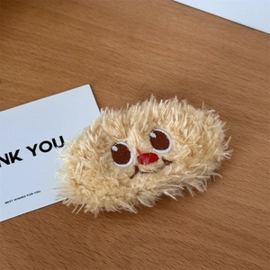 Detailed macro of a cute plush bear hair clip with embroidery on a wooden table