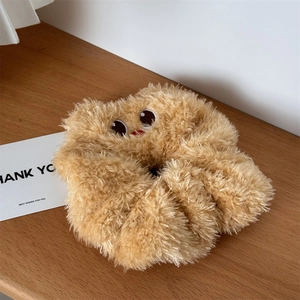 Close-up of fluffy honey butter bear plush hair scrunchie with cute cartoon face on wood
