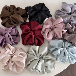 Macro shot of high-quality satin scrunchies in multiple colors with handmade labels