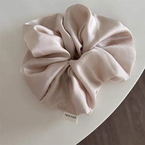 Detail of premium champagne satin oversized scrunchie with a handmade woven label
