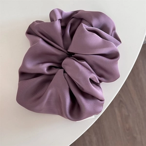 Detailed close-up of glossy purple satin oversized scrunchie with elegant folds