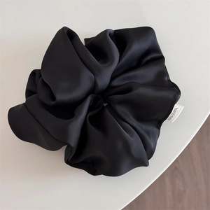 Detail of premium black satin oversized scrunchie featuring a handmade woven label