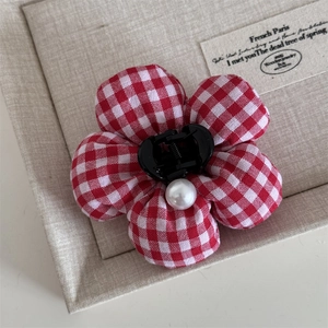 Detail view of a gingham pattern fabric flower hair claw clip with a white pearl center