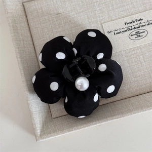 Detailed macro view of the polka dot fabric flower hair claw clip with a center pearl detail