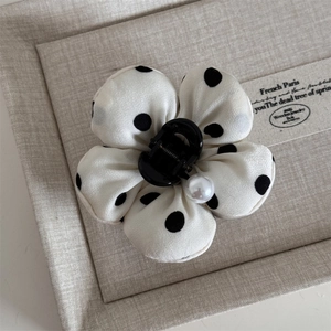 Close-up of French style polka dot fabric flower hair claw with a glossy pearl center