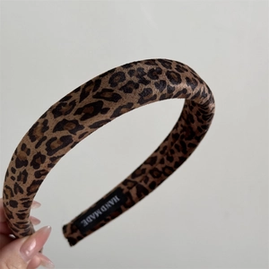 Detailed macro view of leopard print velvet headband with Hand Made woven label