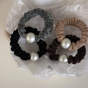 Detail view of shimmering fabric hair scrunchies with white pearls in four elegant colors