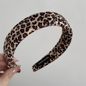 Macro shot of a thick padded leopard print headband showing satin texture and handmade tag