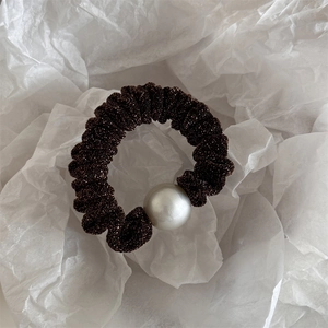 Detail of dark coffee glitter fabric scrunchie with a large matte white pearl charm