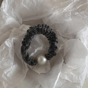 Detail view of black glitter fabric scrunchie with a large white pearl bead embellishment