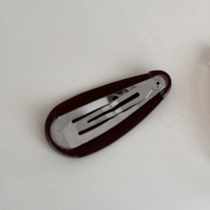 Detail view of a burgundy acetate teardrop BB hair clip with silver metal snap fastener